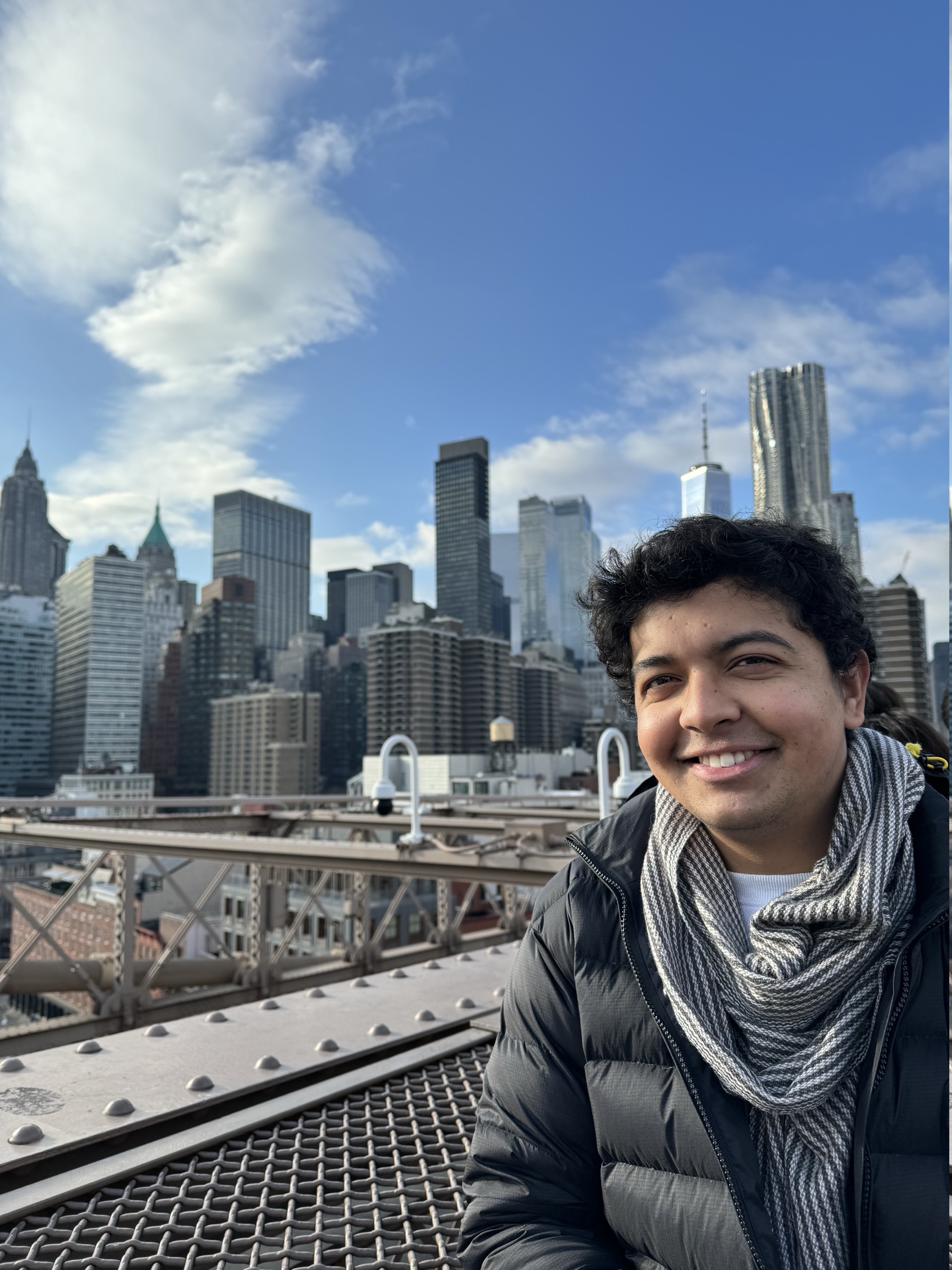 Rasil on the Brooklyn Bridge with the Lower Manhattan skyline behind him