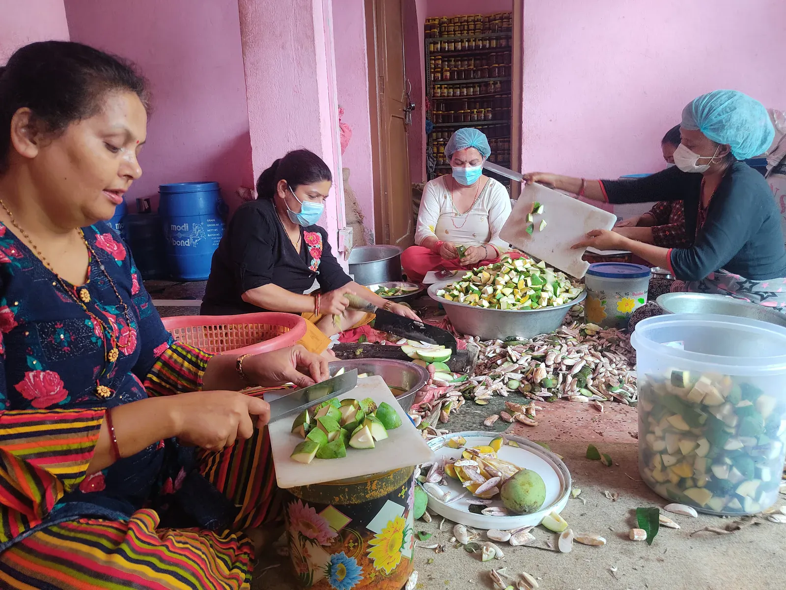 Four women preparing mangoes by hand inside the My Pickle House production space